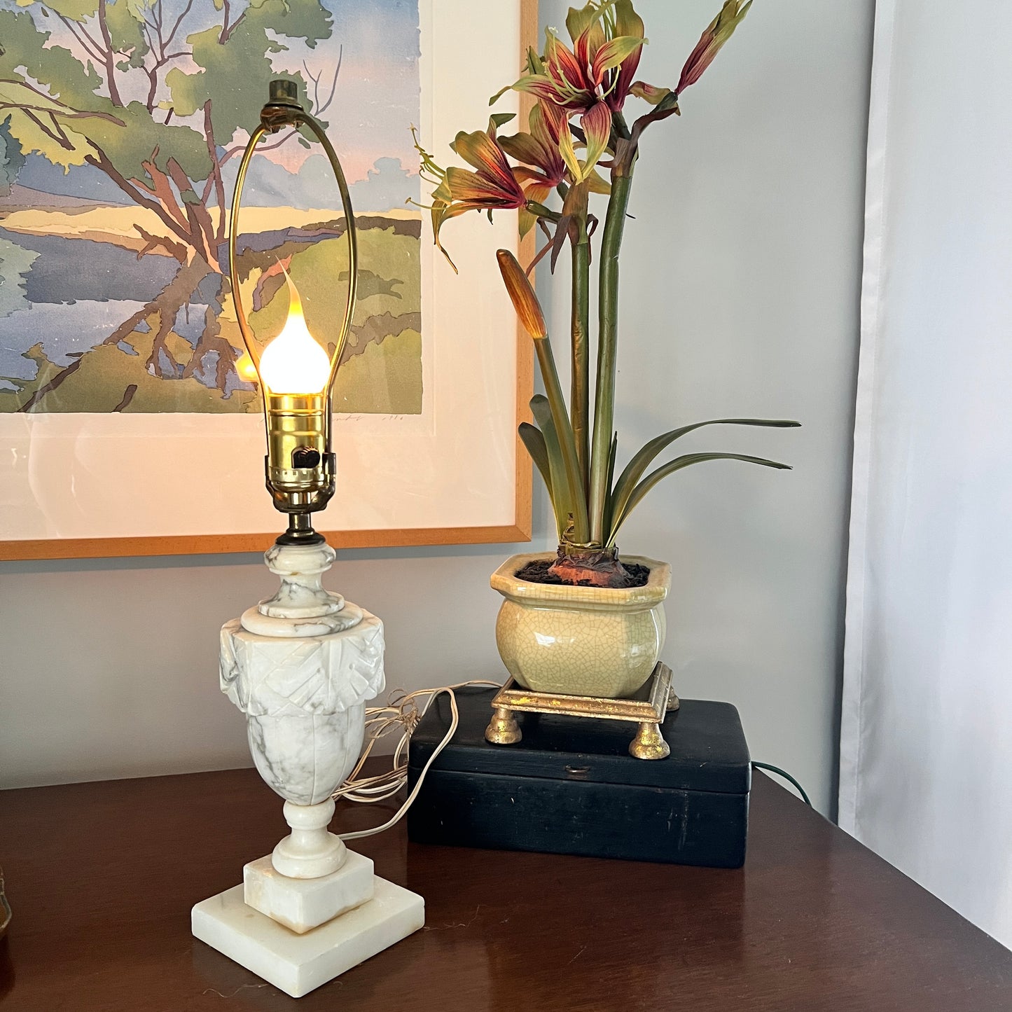Decorative lamp with marble base and a potted plant on a wooden surface.