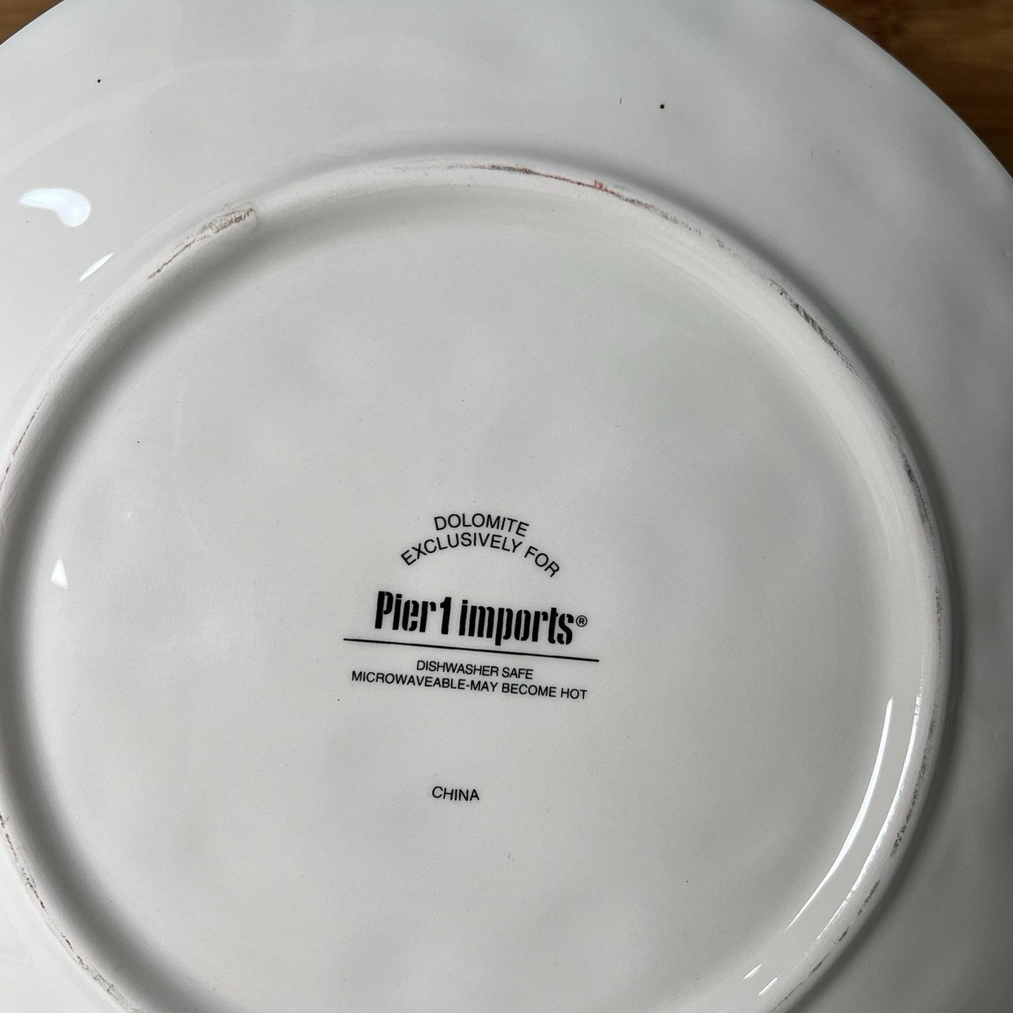 Back of a white plate with 'Pier 1 Imports' branding and product information.