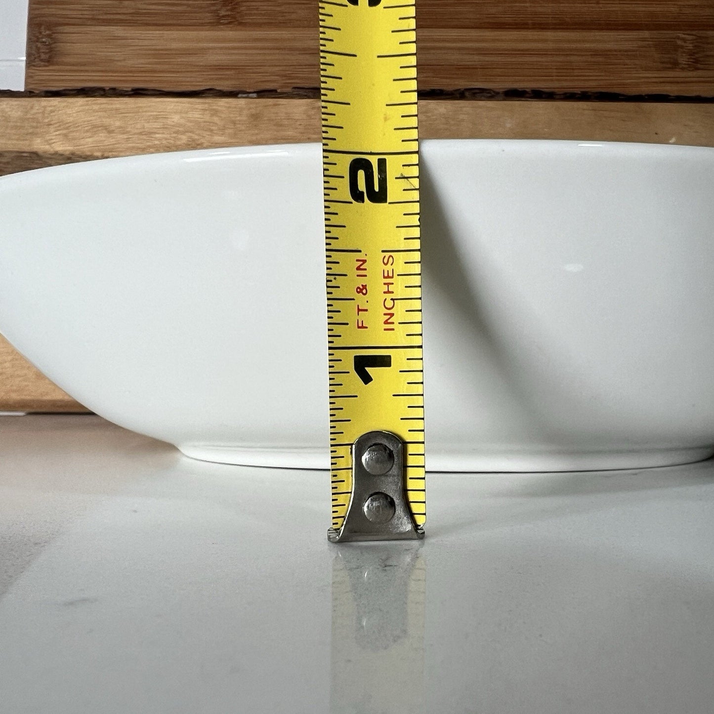 Yellow measuring tape against a white bowl on a wooden surface