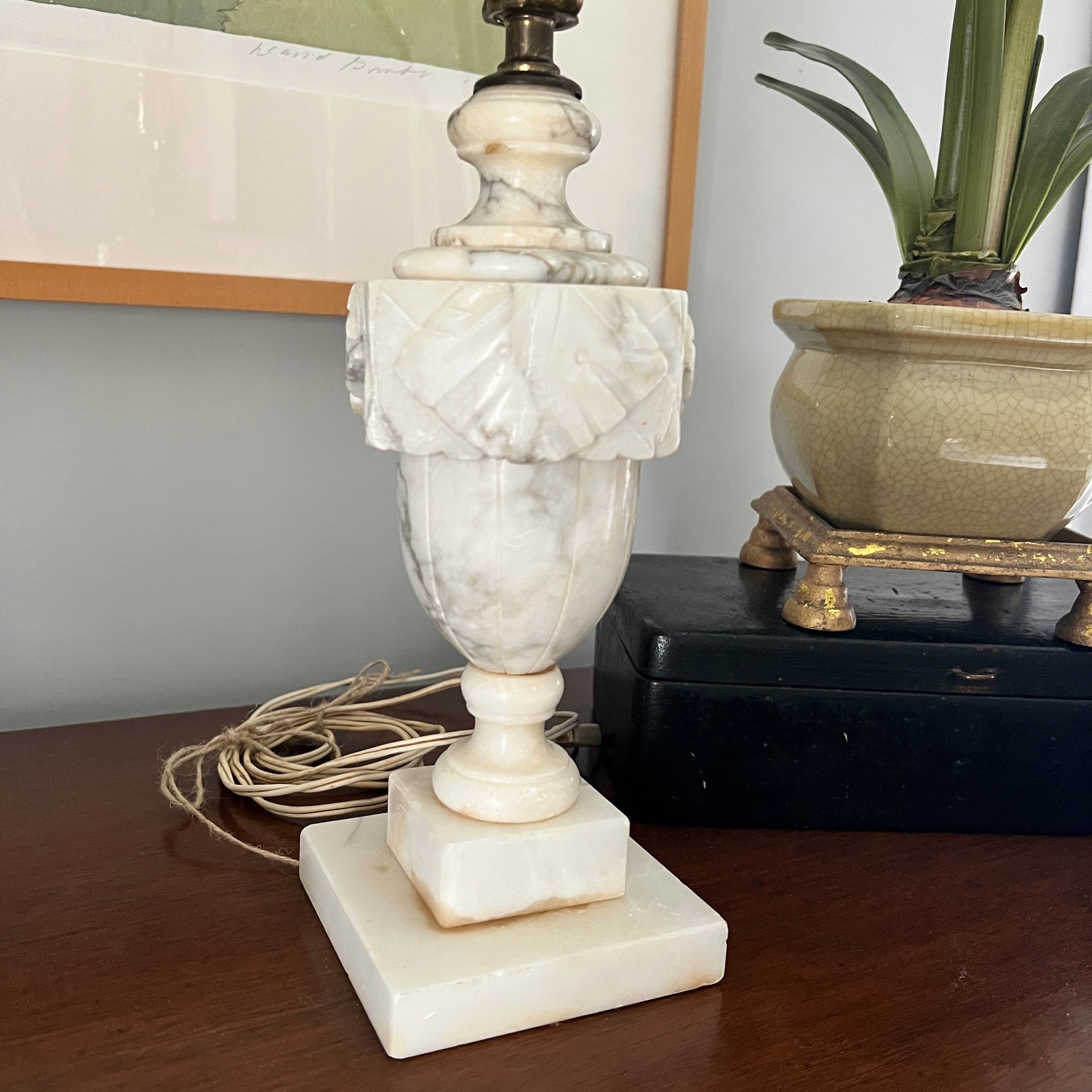 Marble lamp on a wooden surface with a plant in the background