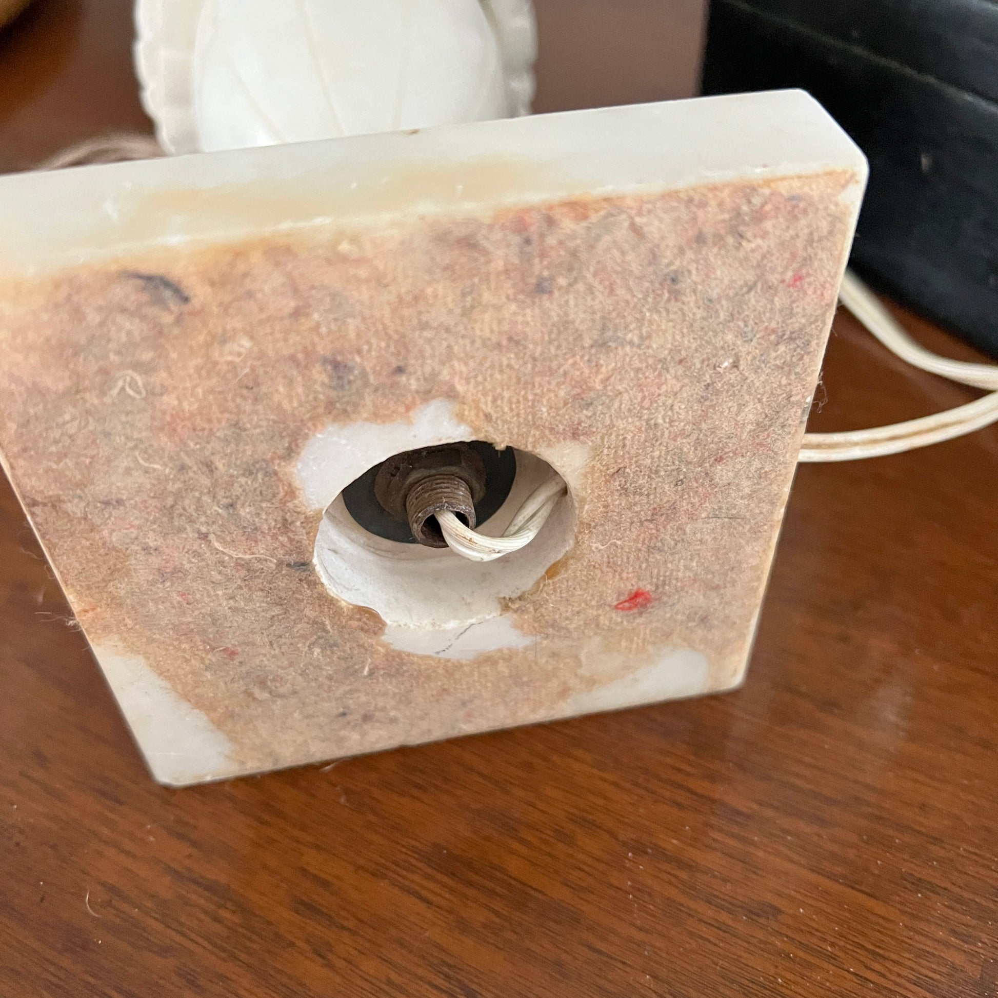 Square stone-like object with a central hole on a wooden surface