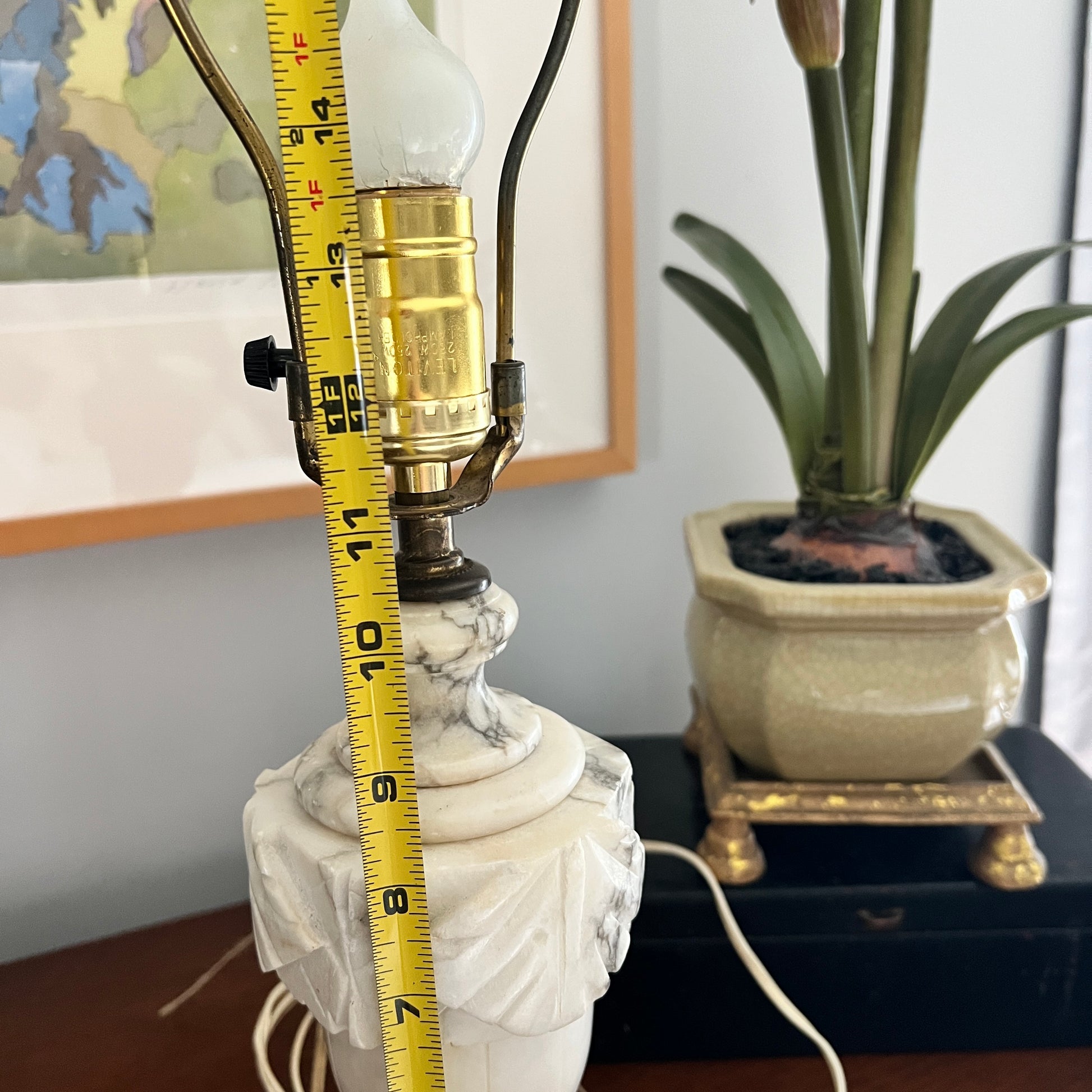 Marble lamp with a light bulb and measuring tape, potted plant in the background