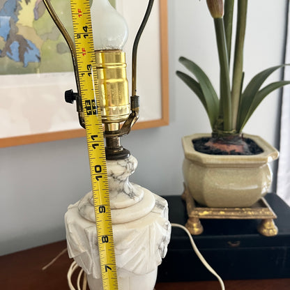 Marble lamp with a light bulb and measuring tape, potted plant in the background