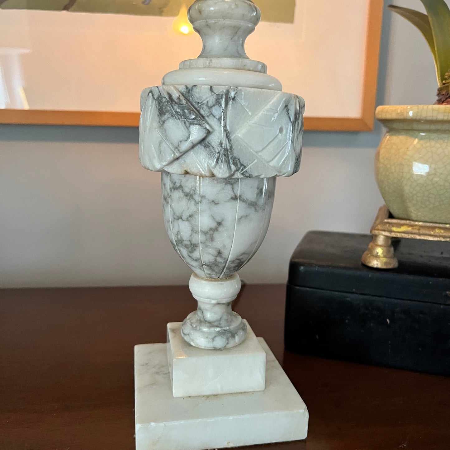 Marble-patterned decorative urn on a wooden surface with a neutral background