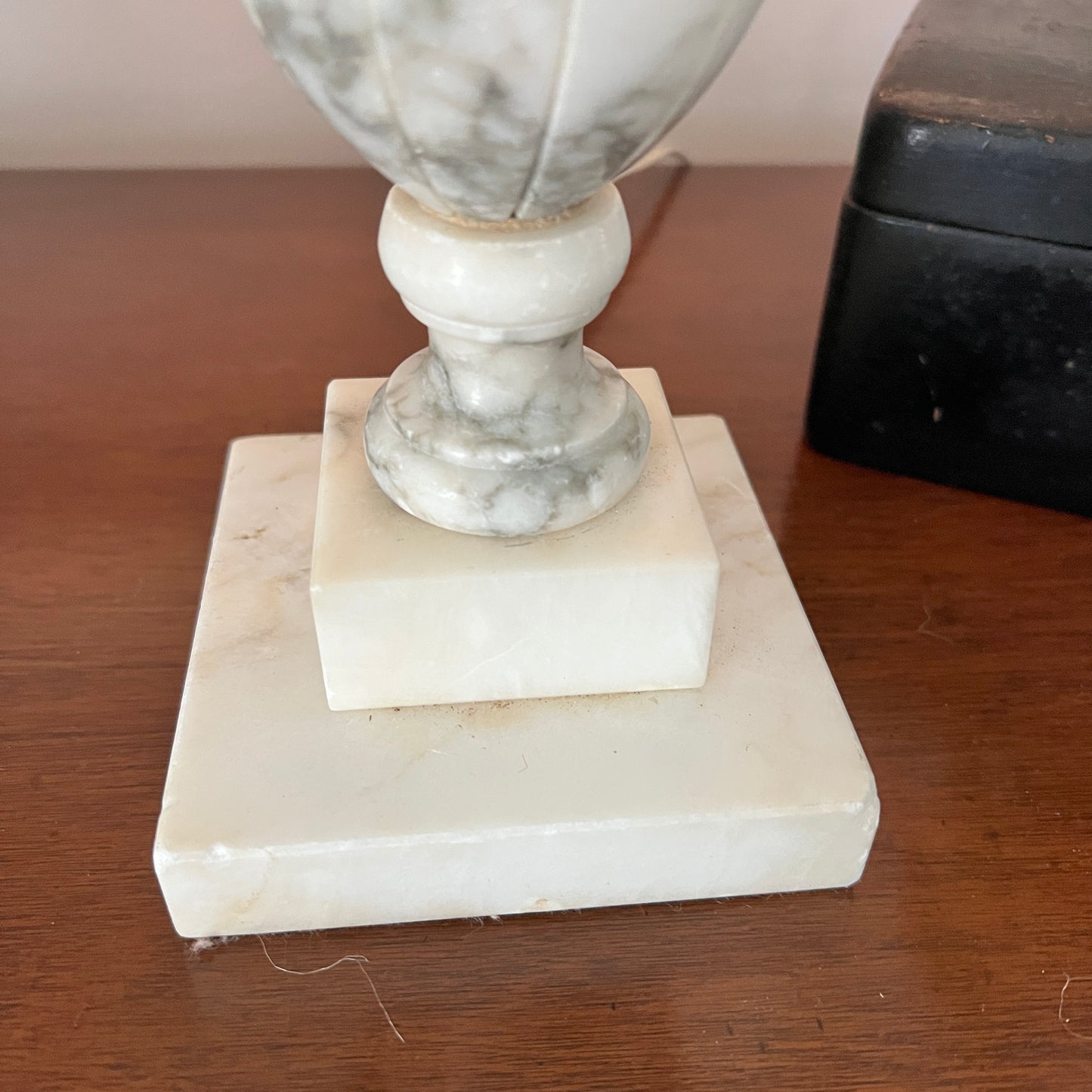 Marble vase on a square marble base on a wooden surface