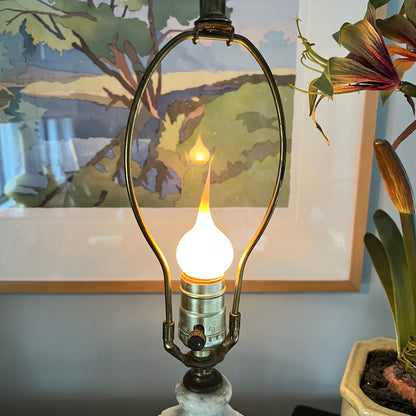 Decorative lamp with a light bulb design in front of a painting