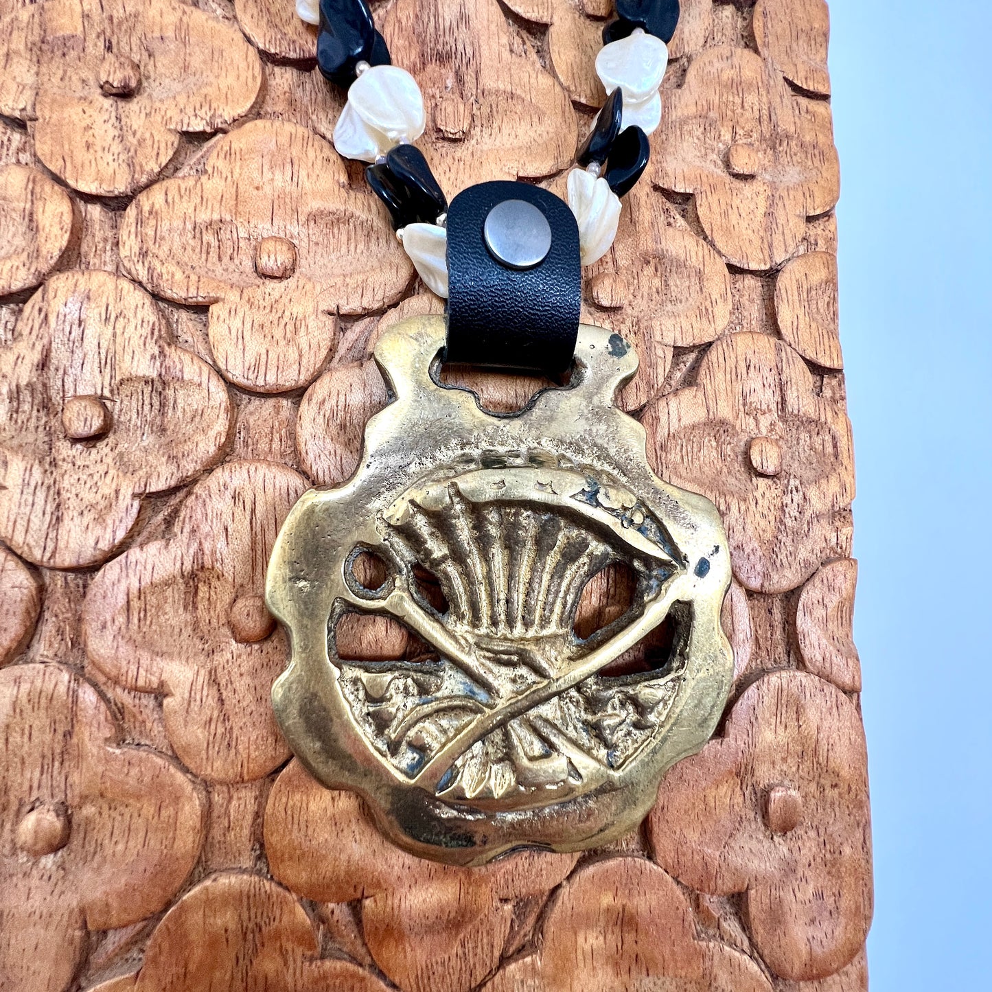Brass medallion with leather strap on a wooden surface