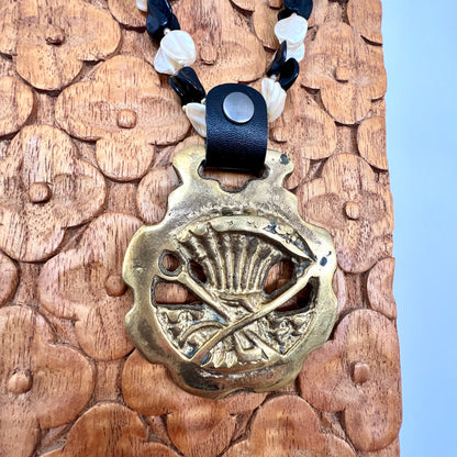 Brass medallion with leather strap on a wooden surface