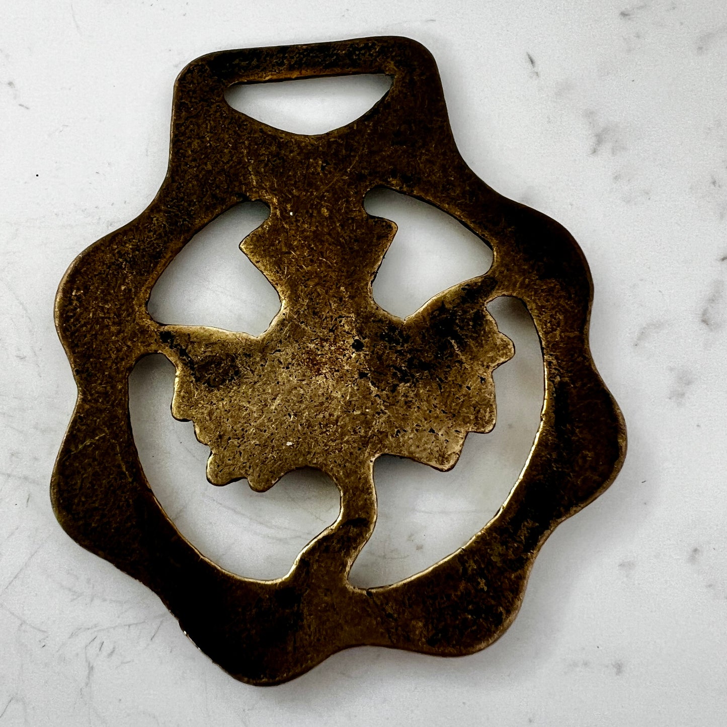 Bronze medallion with decorative design on a white marble surface