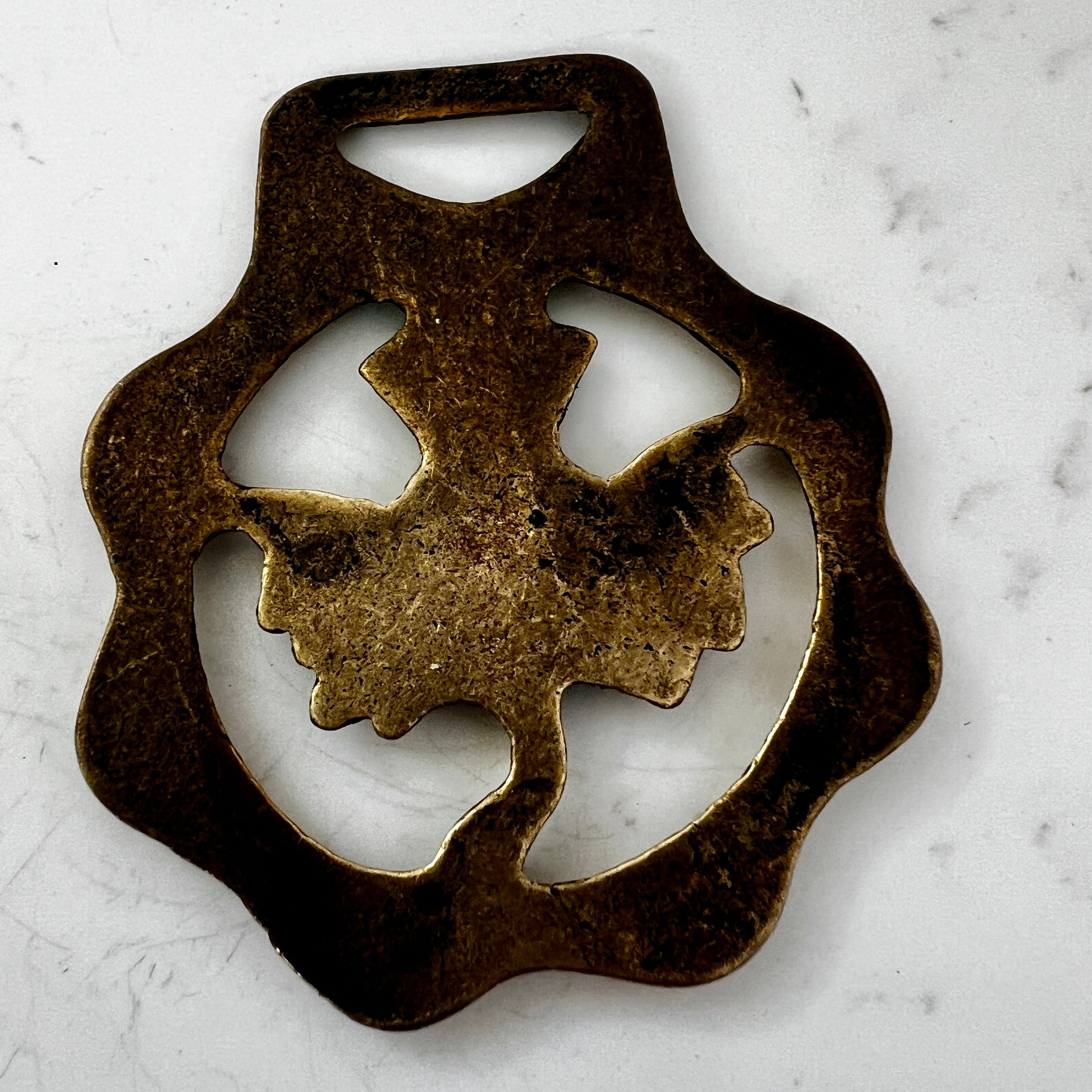 Bronze medallion with decorative design on a white marble surface