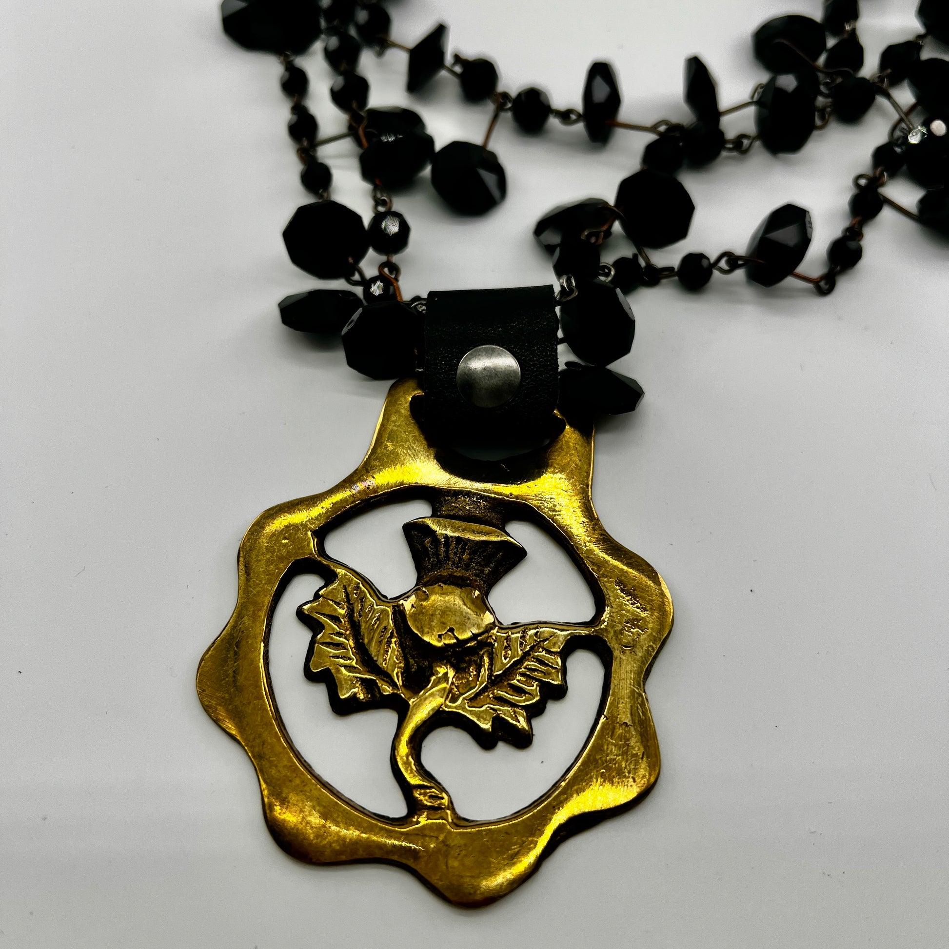 Necklace with a brass pendant featuring a bird design on a white background