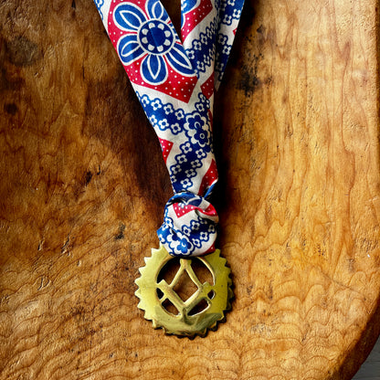 Vintage Masonic square and compass brass medallion necklace with red white blue scarf on wood background