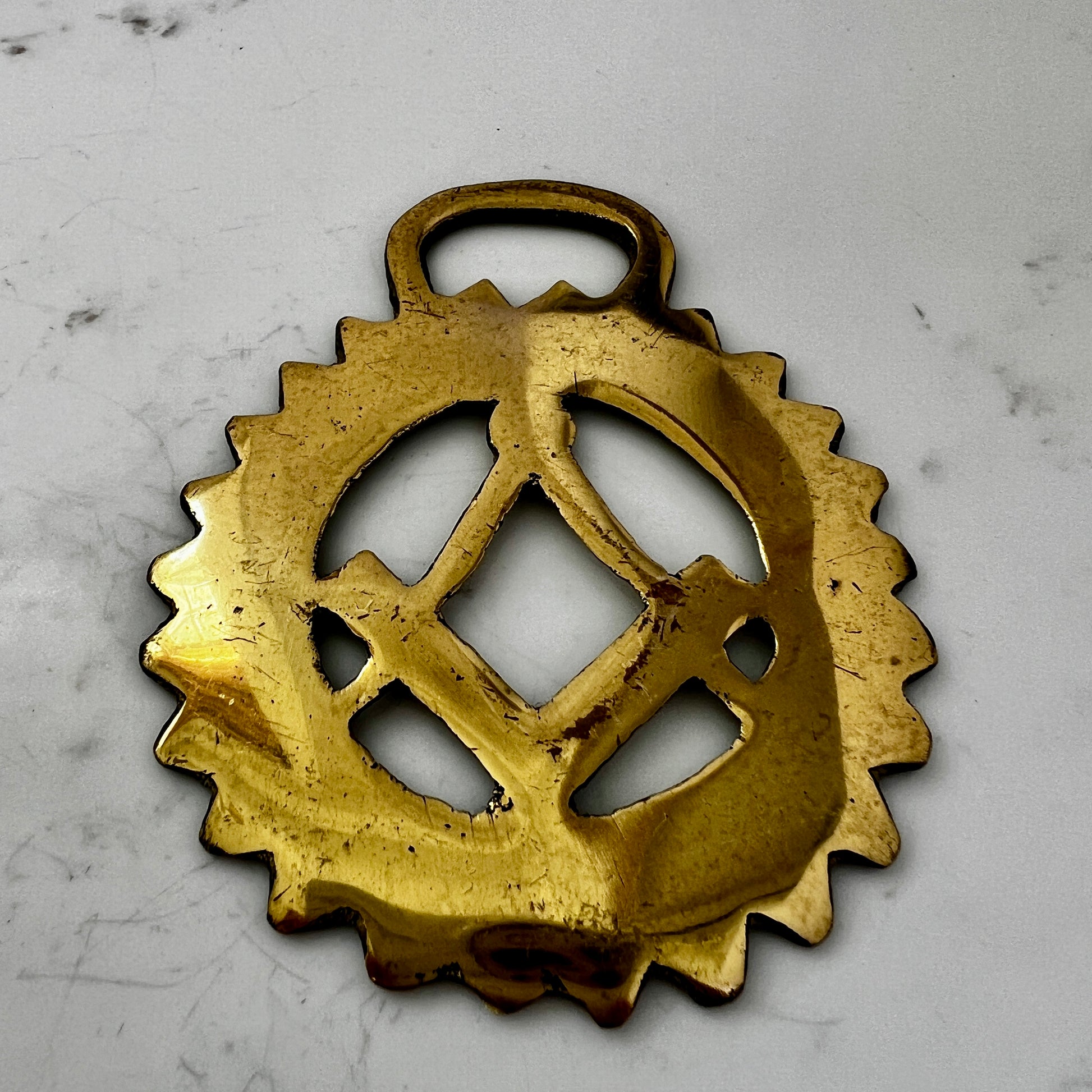 Gold decorative object with intricate design on a light gray background