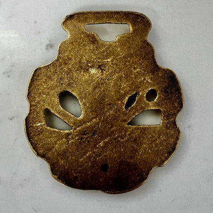 Bronze decorative object with cut-out shapes on a gray background
