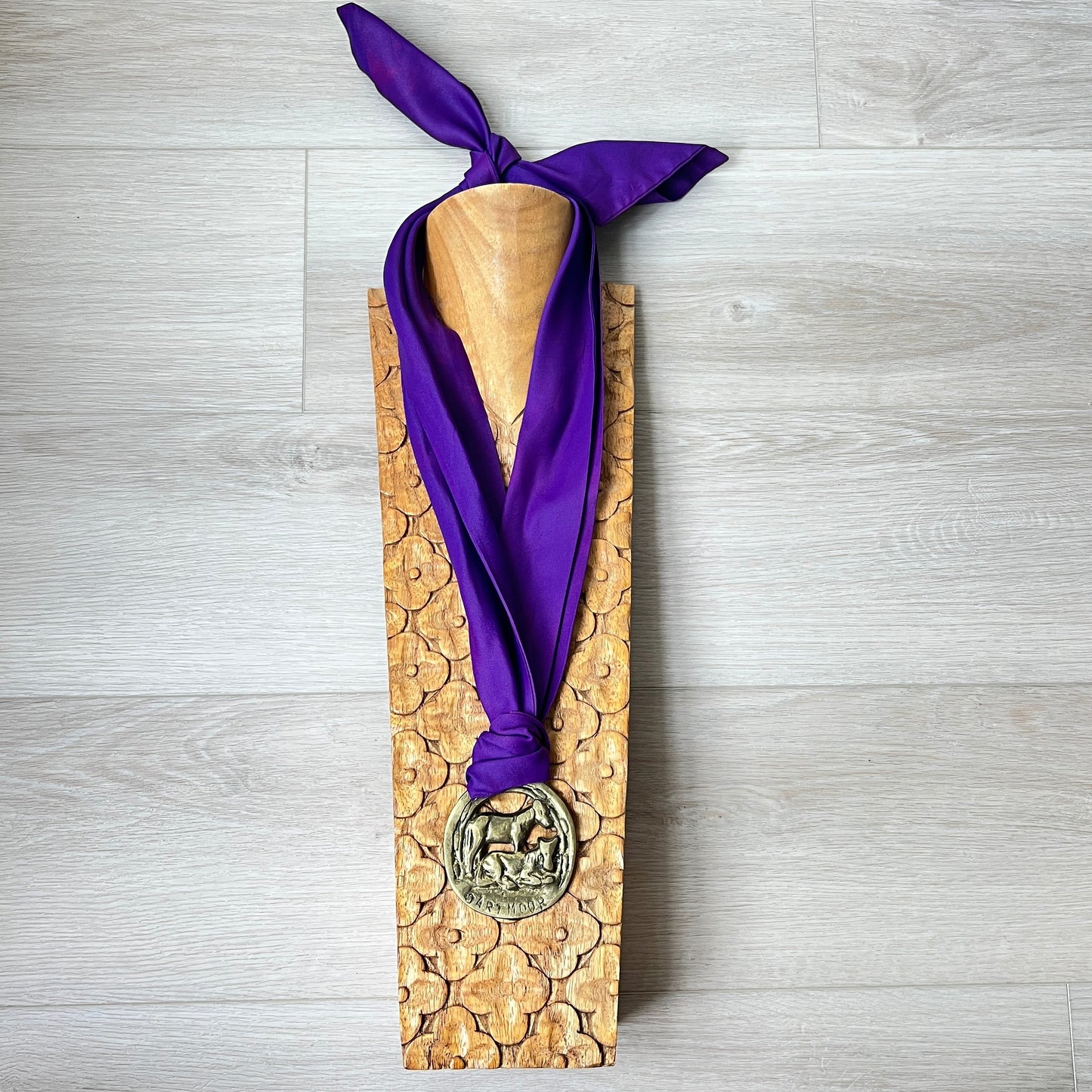 Wooden plaque with a purple ribbon and silver medal on a gray wooden surface