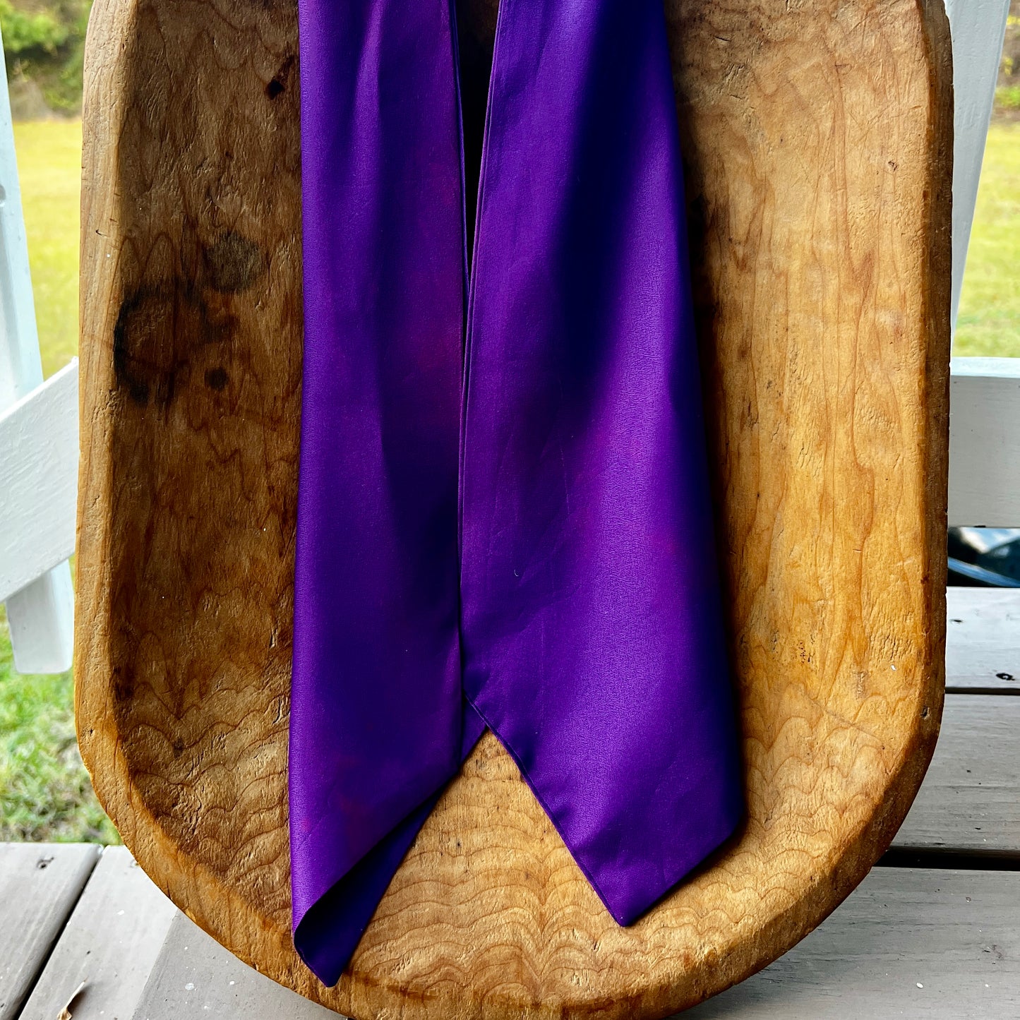 Purple fabric draped over a wooden bowl outdoors