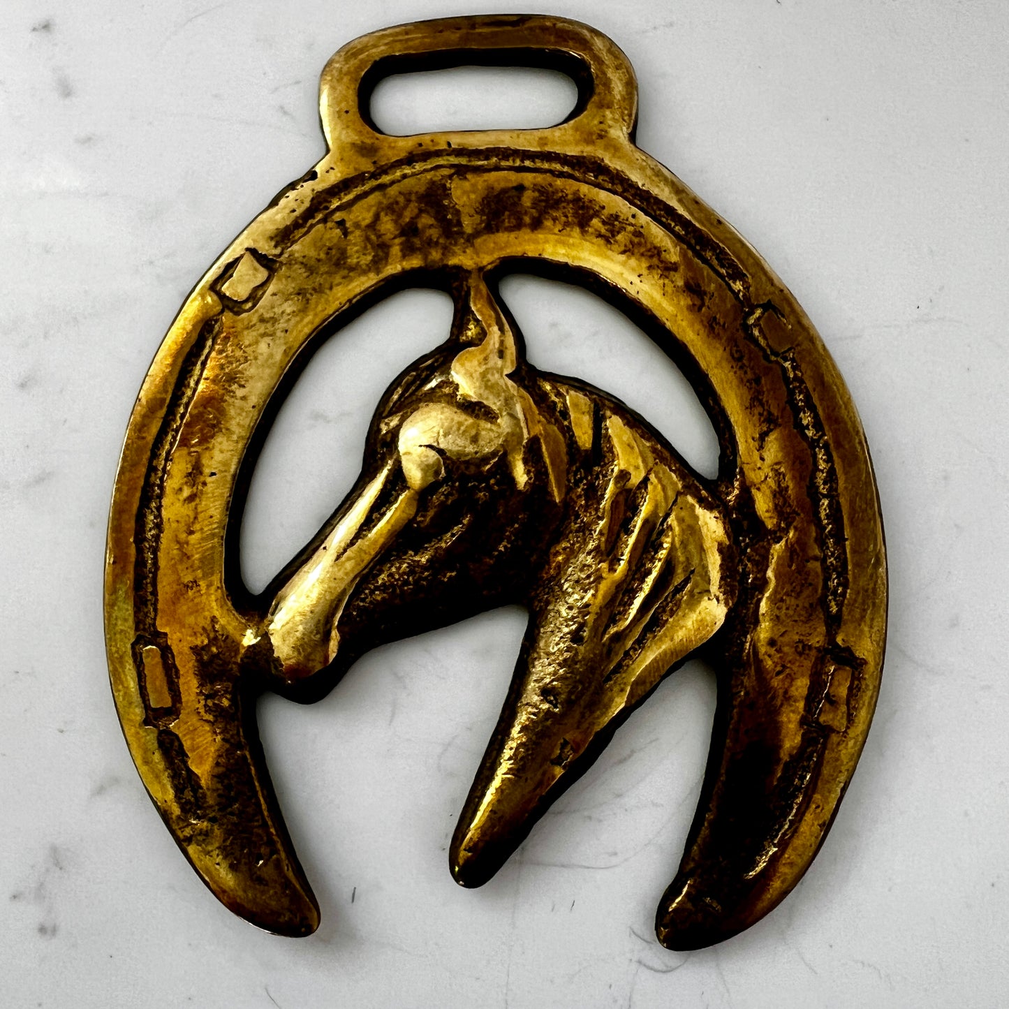 Vintage horse brass medallion attached to multi-strand wooden bead necklace with caramel leather connector.