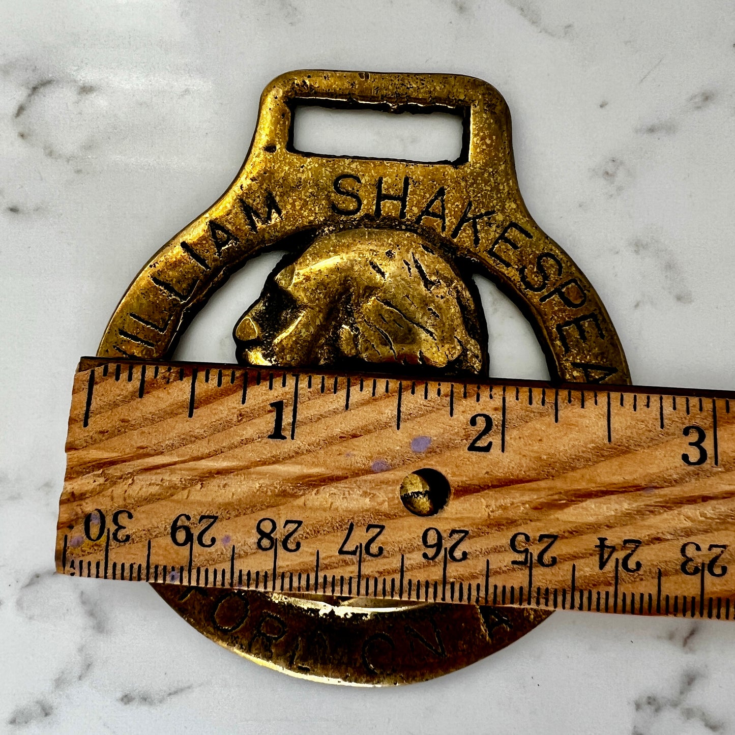 Vintage William Shakespeare horse brass medallion attached to brown leather keychain with brass ring and clip.