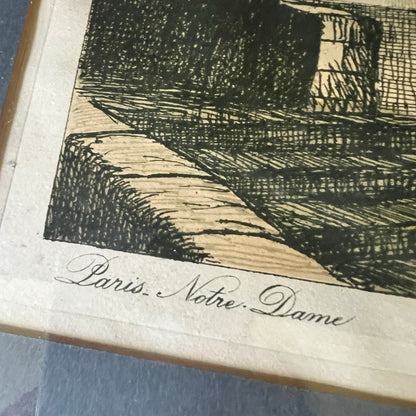 A close-up of an etched or printed artwork showing a dark ink landscape scene on aged off-white paper, with the cursive text 'Paris Notre Dame' visible along the bottom edge.