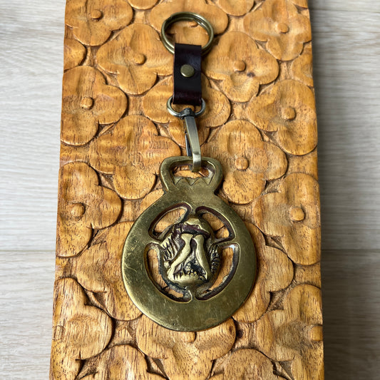 Bronze keychain with a design on a wooden surface