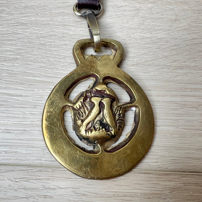 Gold pendant with a love birds design on a wooden surface