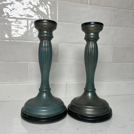 Two blue candle holders on a white tiled floor.
