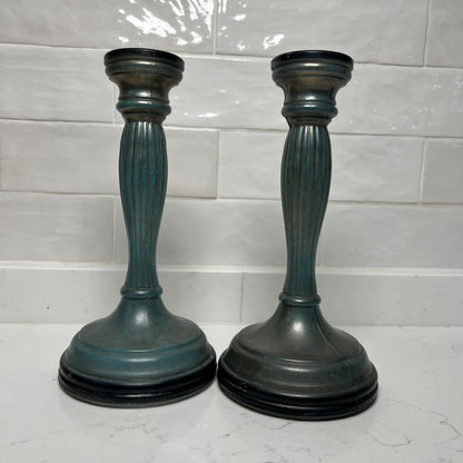 Two blue candle holders on a white surface with a tiled wall background