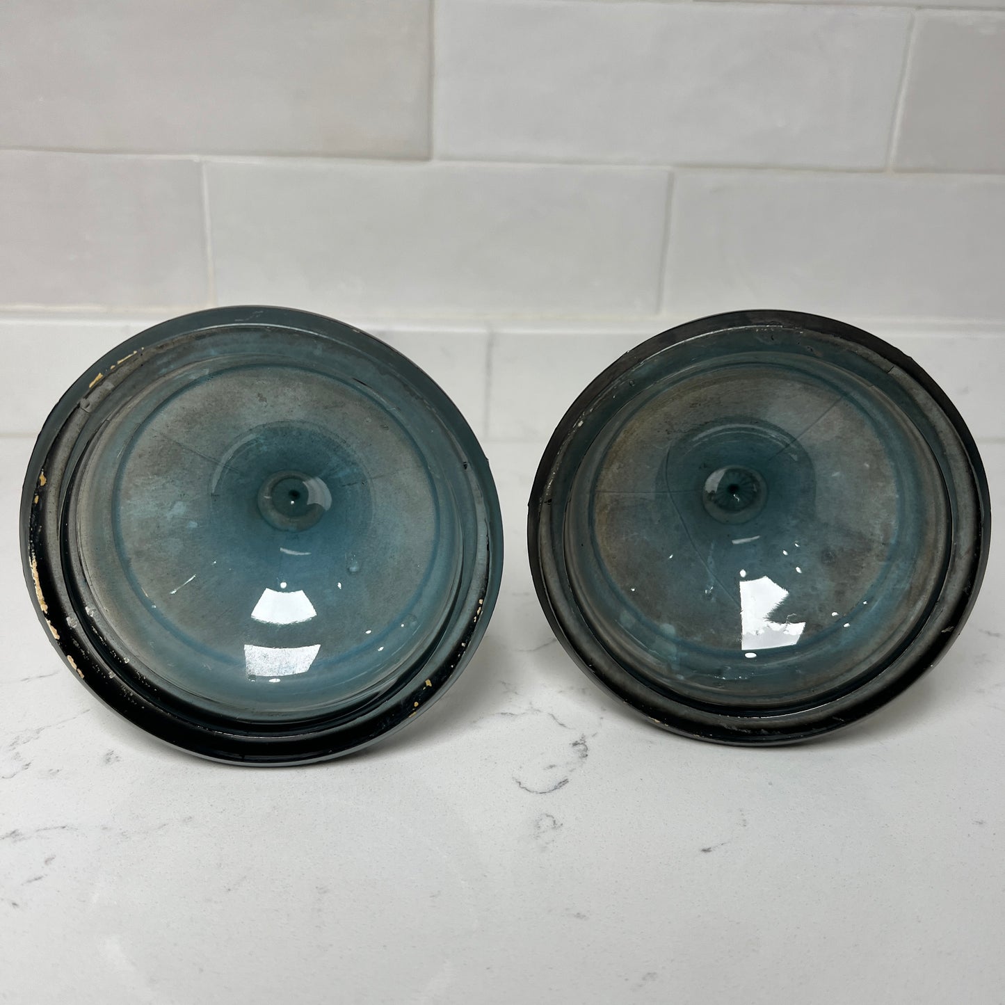 Two black and blue bottom of candlesticks on a white tiled surface