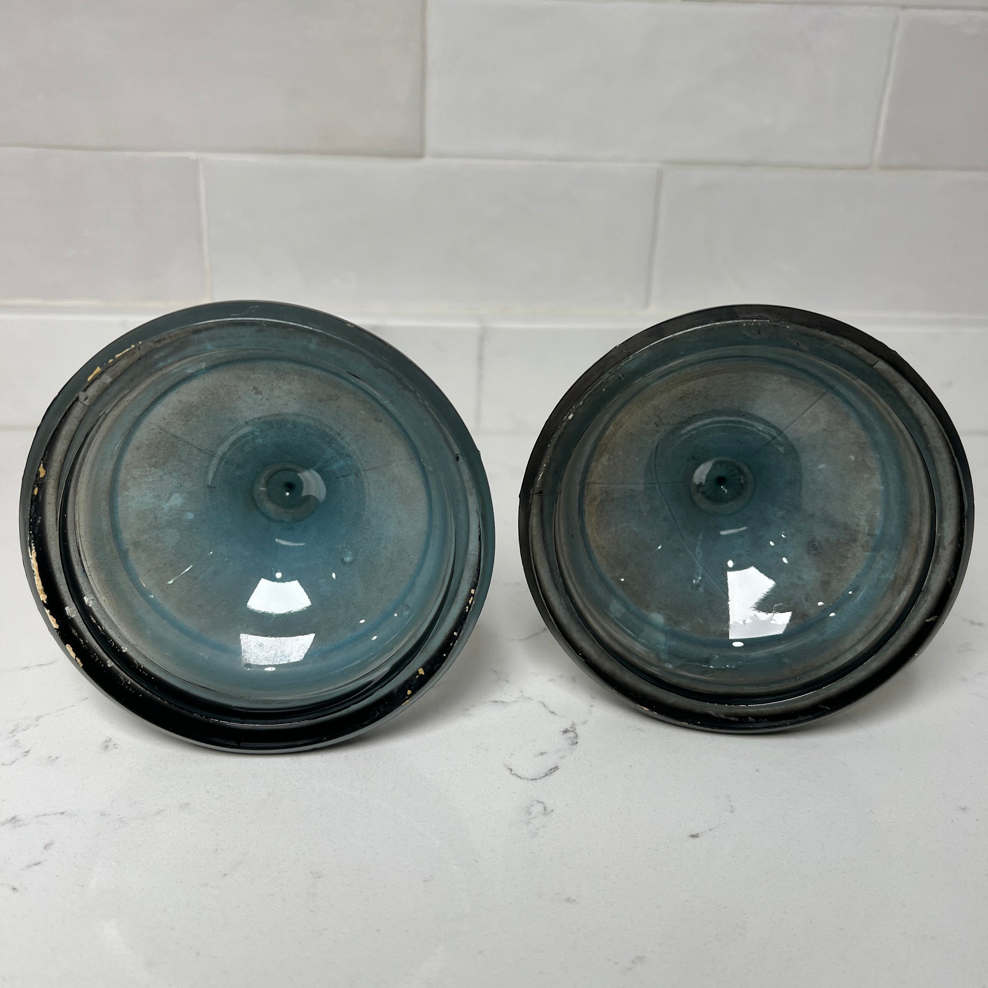 Two black and blue bottom of candlesticks on a white tiled surface