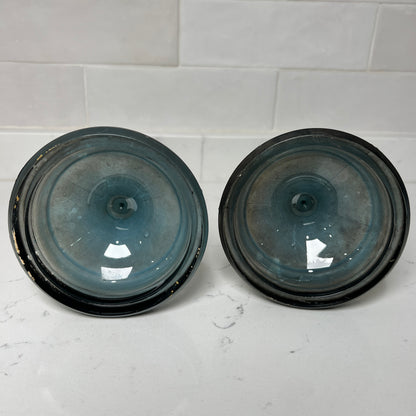Two black and blue bottom of candlesticks on a white tiled surface