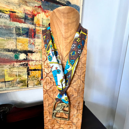 Mannequin head with a colorful scarf draped over it against a wall with abstract art.