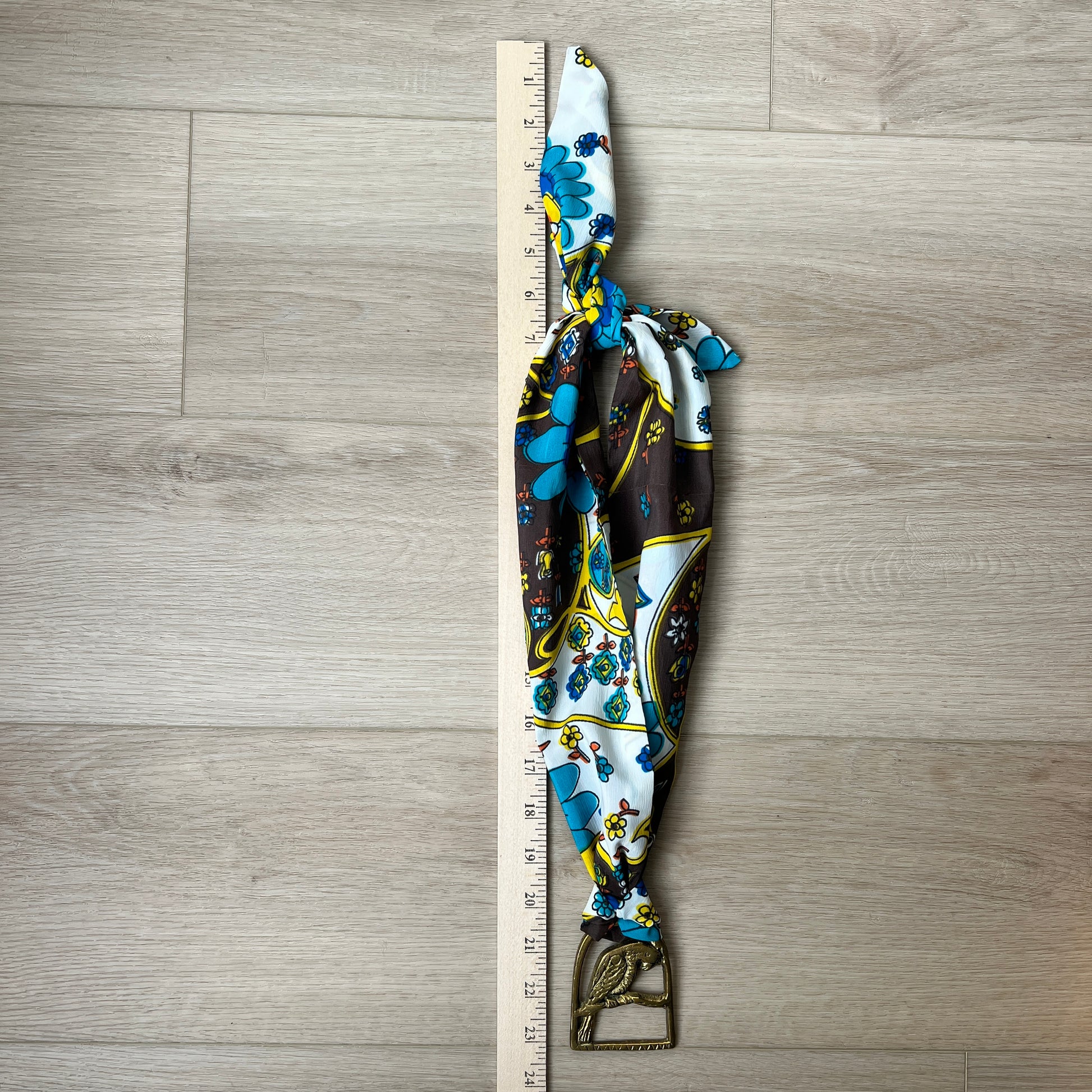 Decorative necklace with floral pattern next to a ruler on a wooden surface