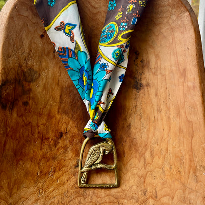 Decorative ribbon with floral pattern and brass medallion on a wooden surface