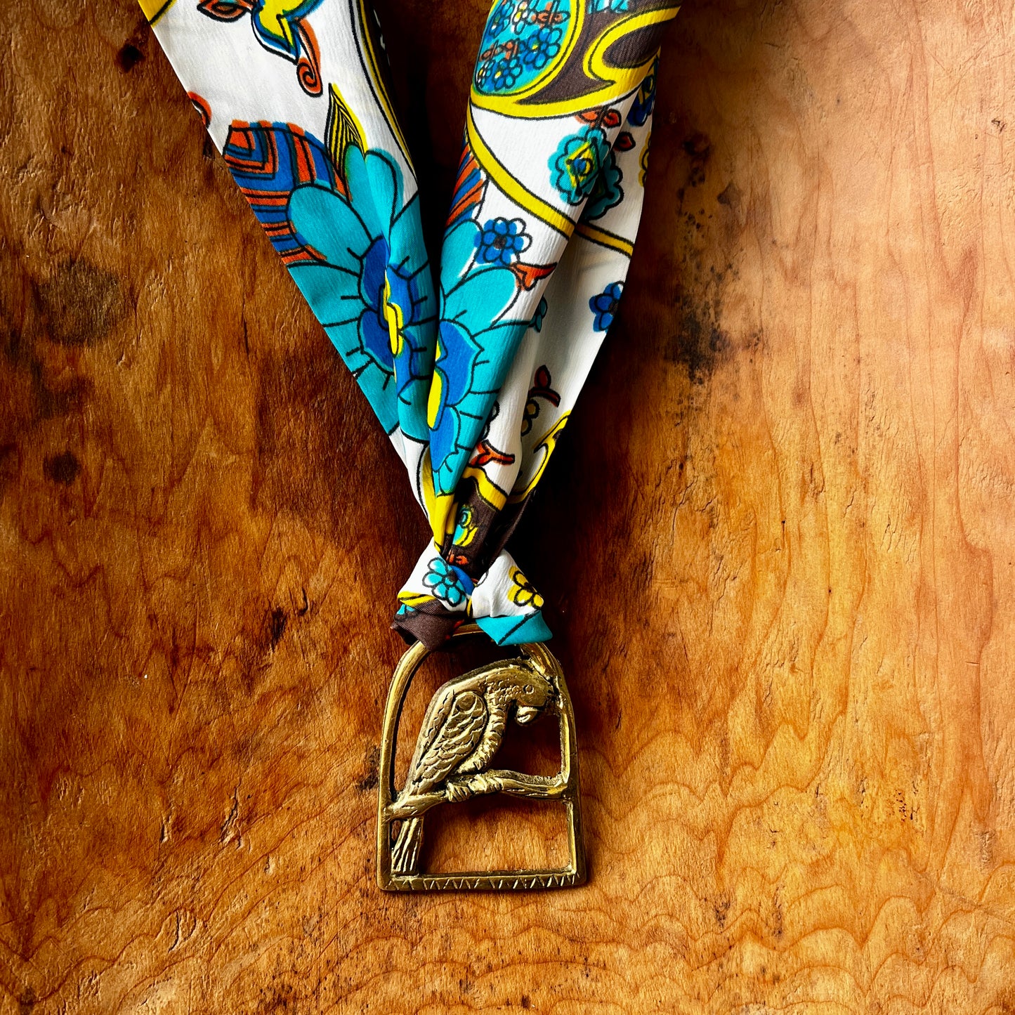 Decorative necklace with floral pattern and brass medallion on a wooden surface