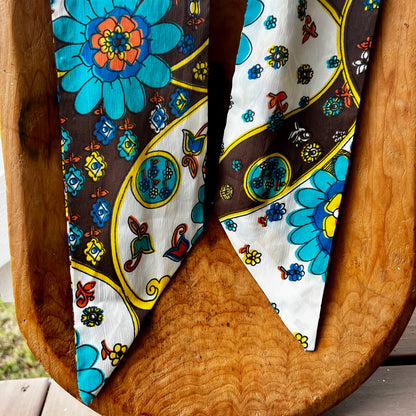 Two colorful floral-patterned scarves on a wooden surface