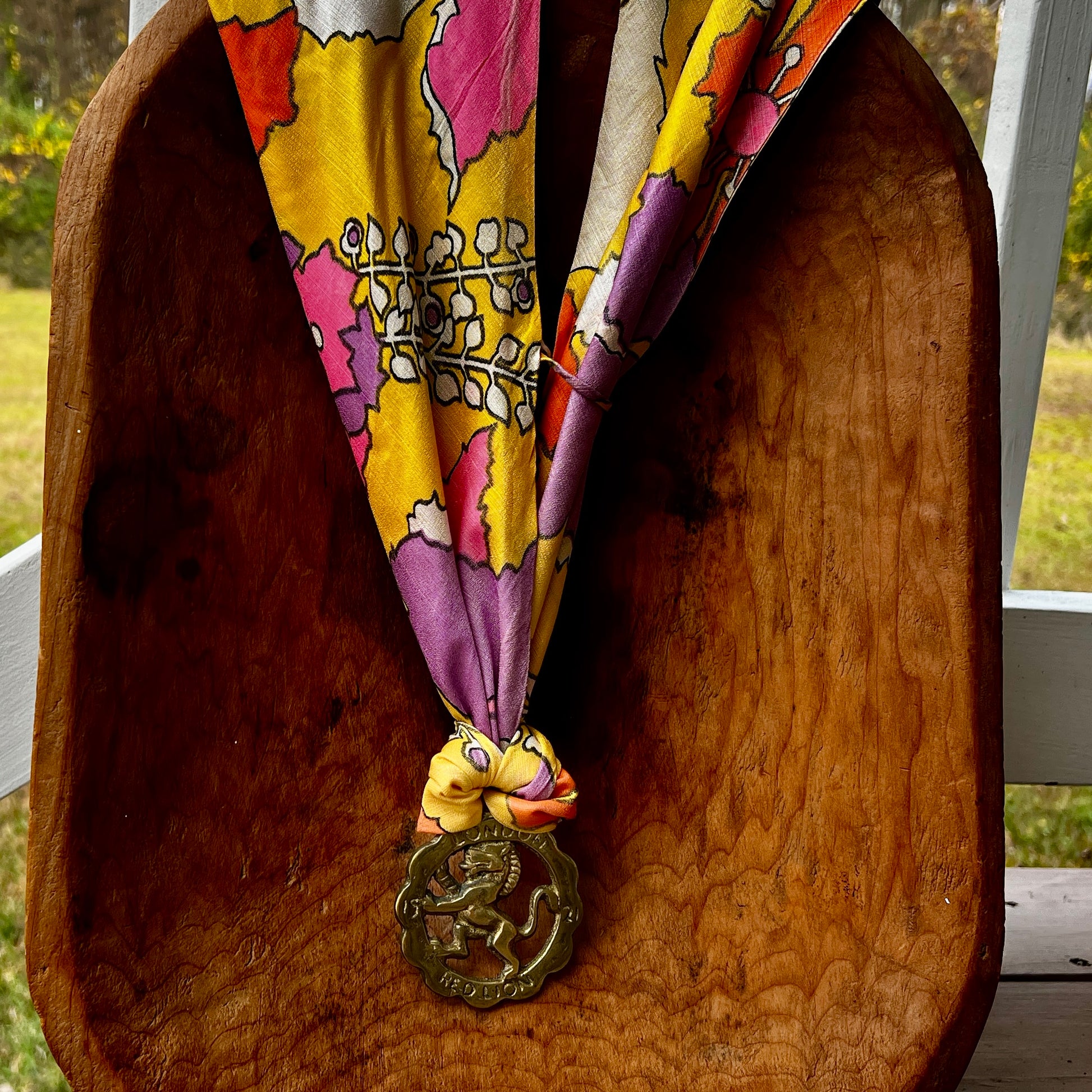 Colorful patterned scarf with a decorative medallion on a wooden surface