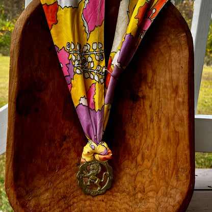 Colorful patterned scarf with a decorative medallion on a wooden surface