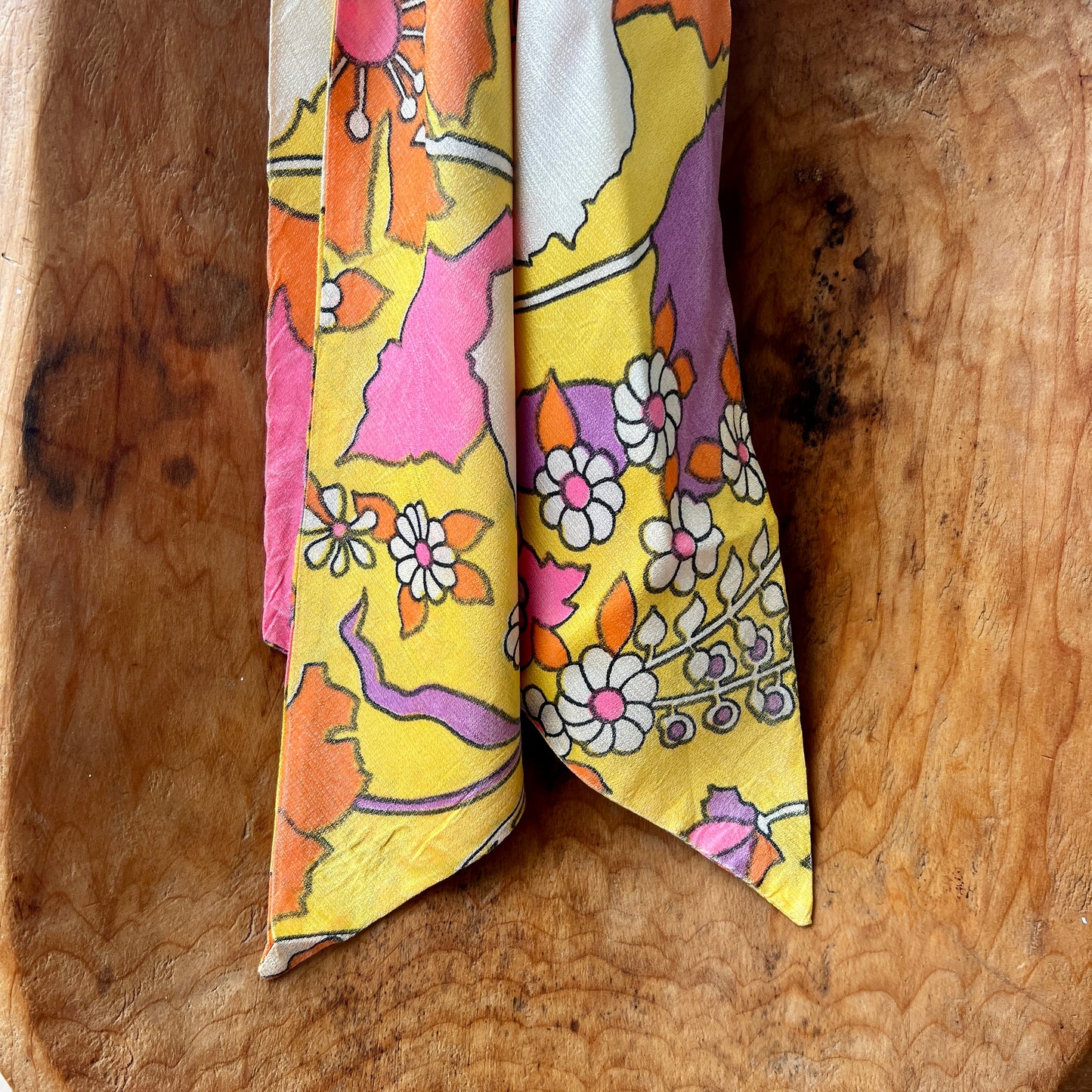 Colorful floral-patterned fabric folded and placed on a wooden surface