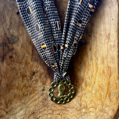 Vintage horse brass medallion necklace with geometric scarf, rustic equestrian jewelry on wooden background