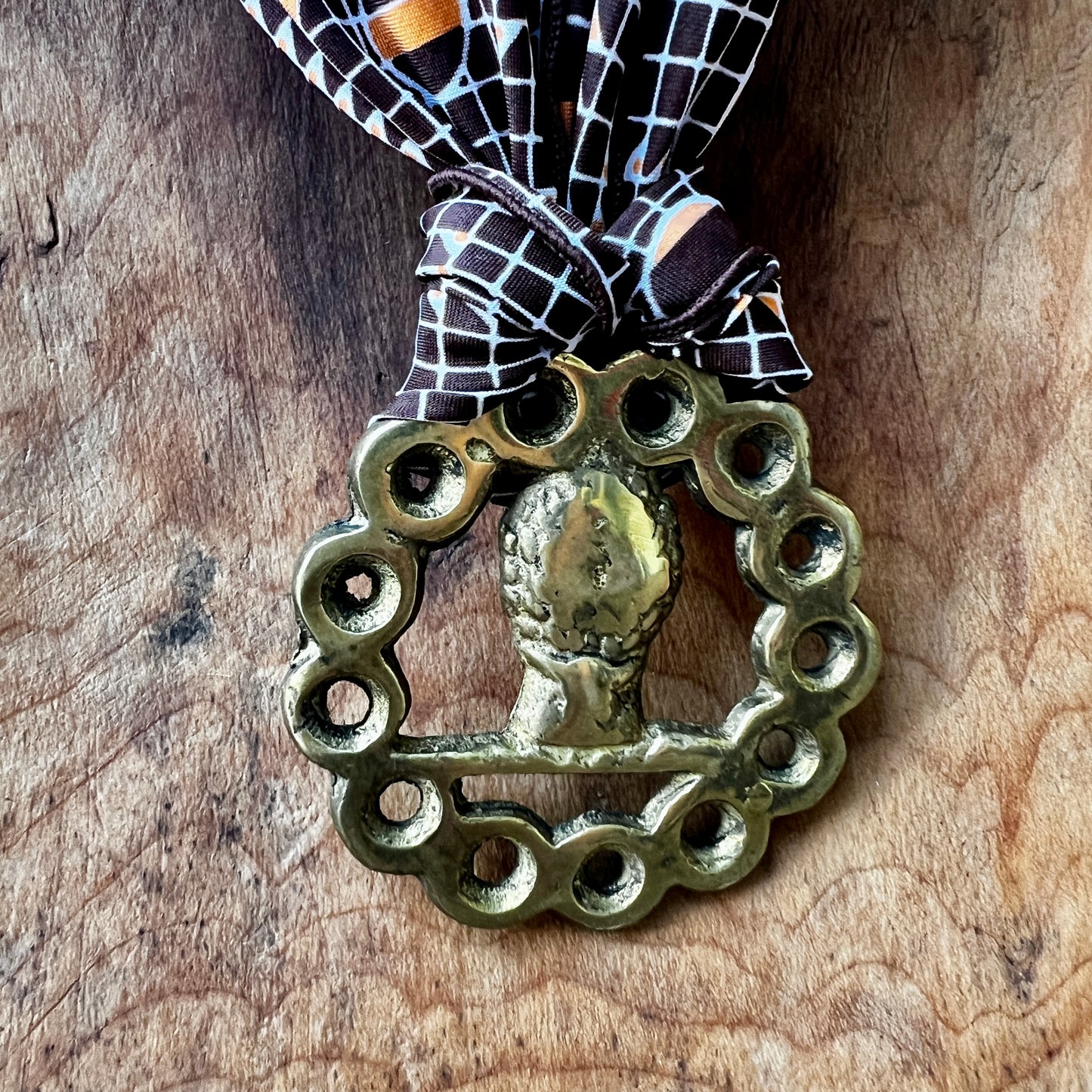 Decorative brass ornament with a bow on a wooden surface