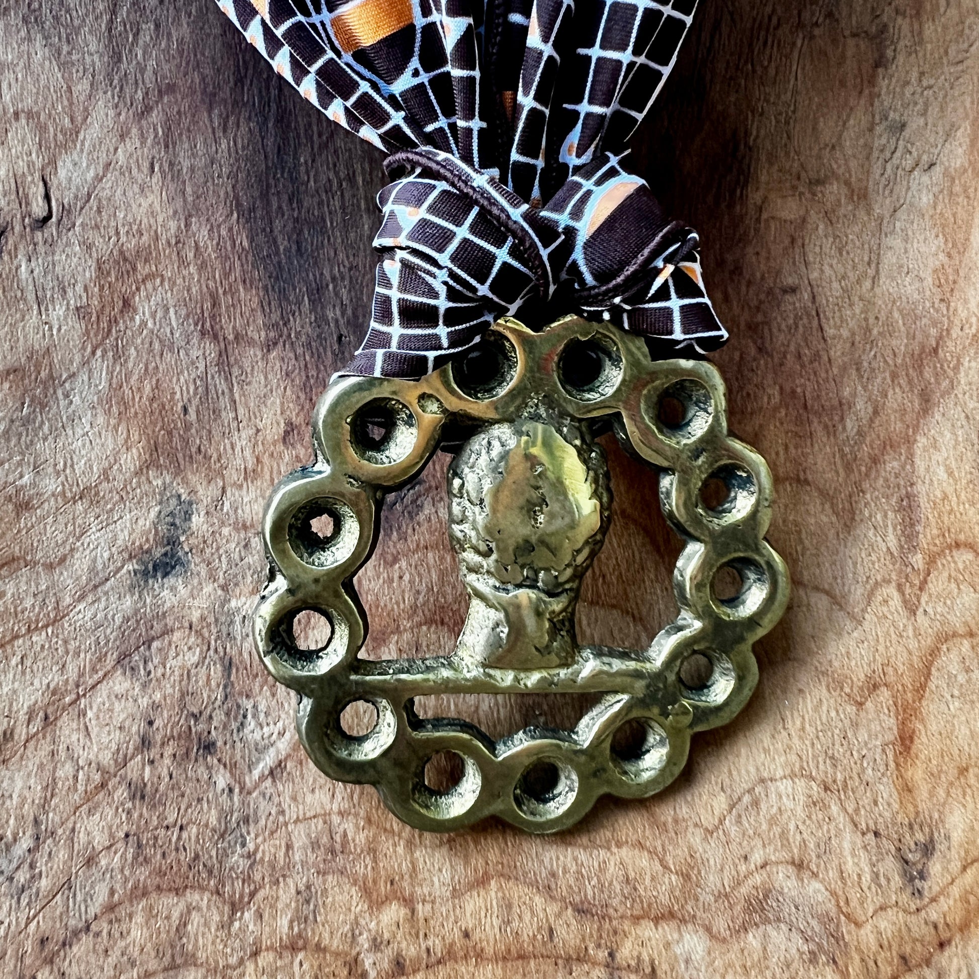 Decorative brass ornament with a bow on a wooden surface