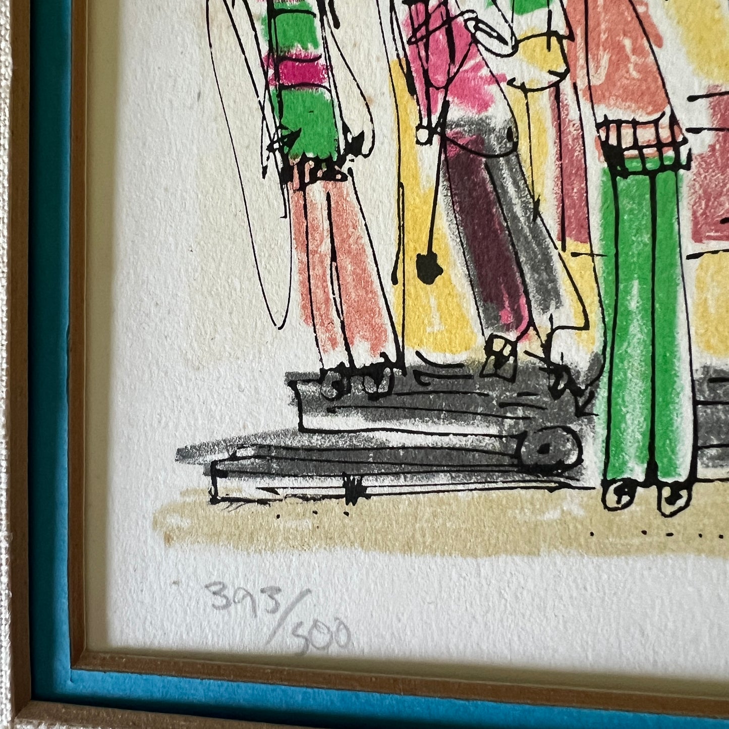 A framed art print featuring a colorful, hand-drawn sketch of figures on a textured off-white paper background. The artwork uses expressive crayon or pastel strokes in green, pink, yellow, and brown, with black sketch lines.