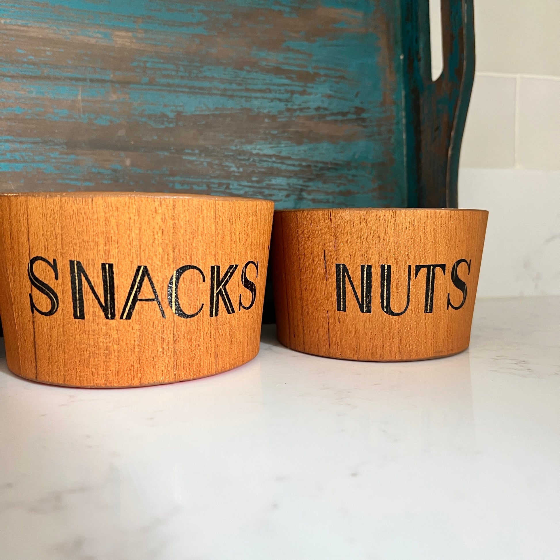 teak snack bowl set with bold orange interior blue tray on white marble says snacks on one and nuts on the other