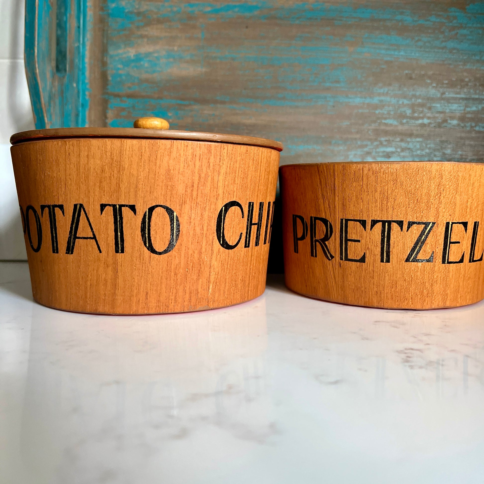 Two wooden containers labeled 'Potato Chip' and 'Pretzel' on a marble surface with a rustic background.