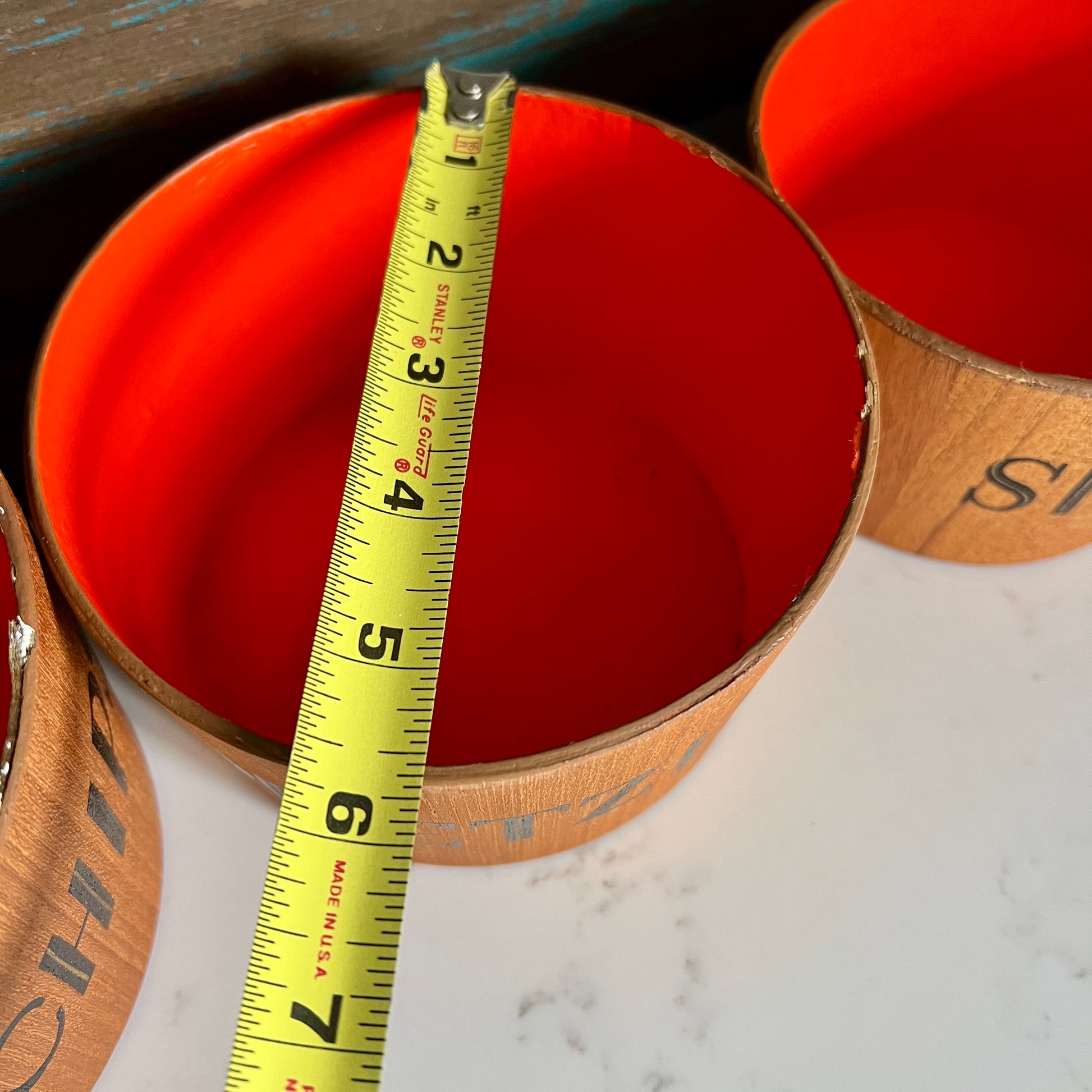 orange bucket with a measuring tape inside, on a marble surface