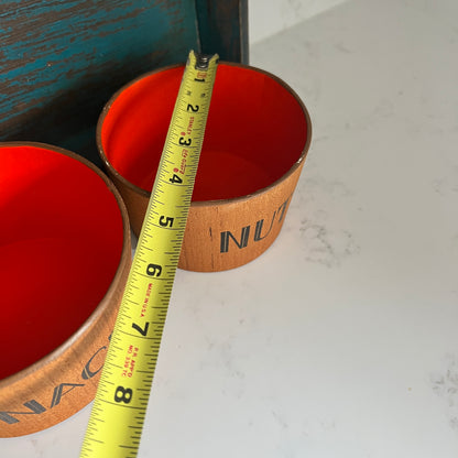 Two orange containers with wooden lids on a white surface, measured by a yellow tape measure.