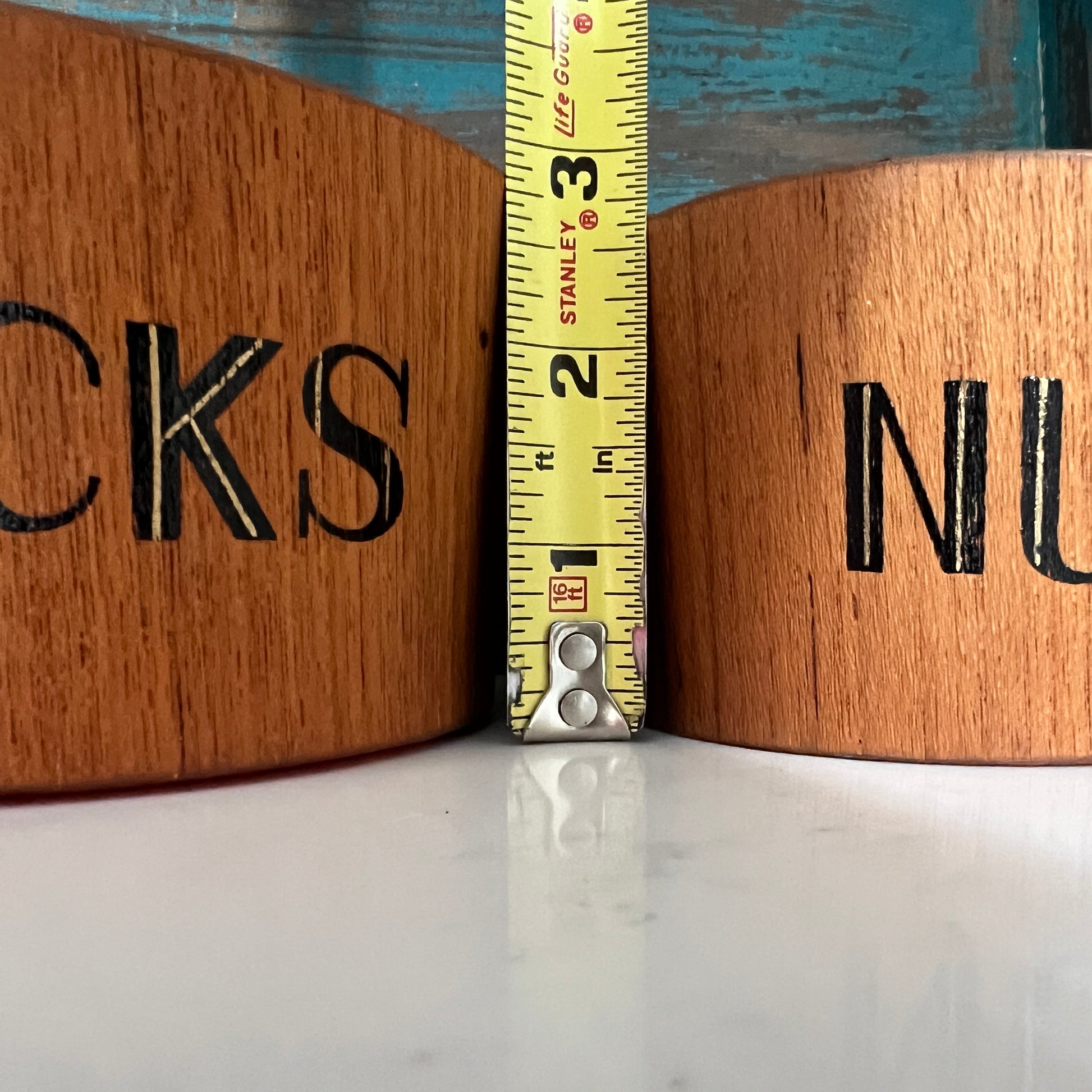 Two wooden bowls with letters and a measuring tape between them.
