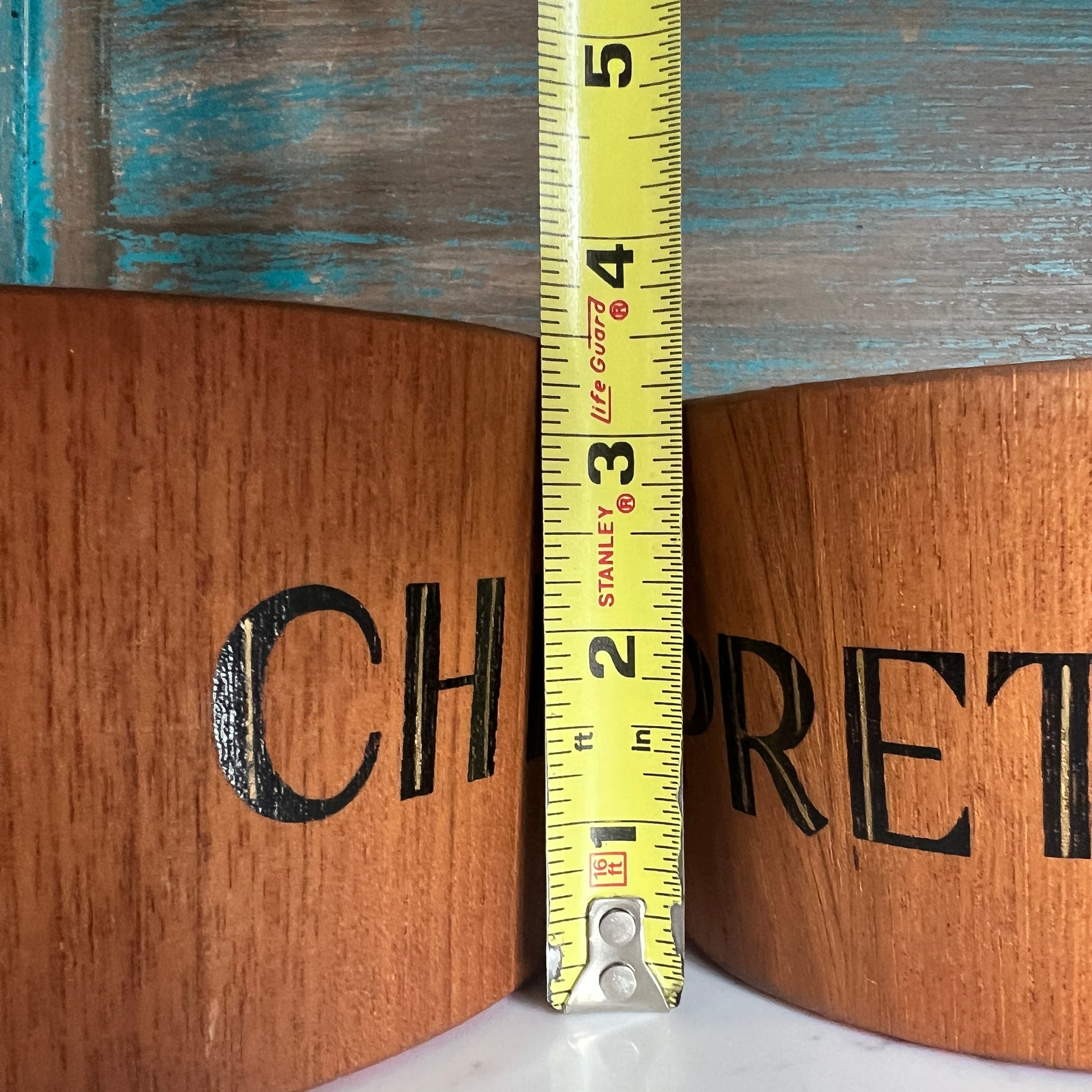 Wooden box with  branding and a measuring tape indicating dimensions.