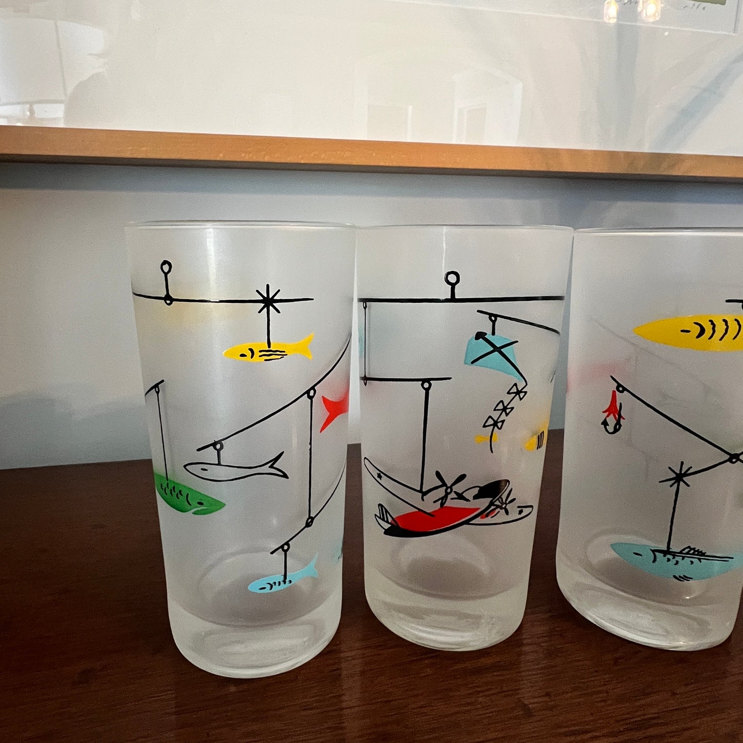 Three frosted glasses with fishing-themed illustrations on a wooden surface.