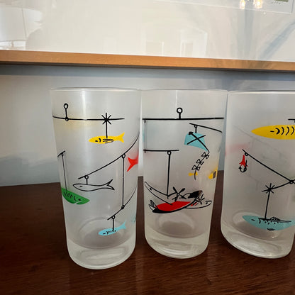 Three frosted glasses with fishing-themed illustrations on a wooden surface.